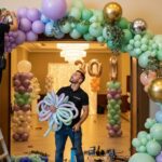 Decoradores profesionales trabajando en arco orgánico de globos con colores pastel, dorados y plateados para fiesta de cumpleaños número 30